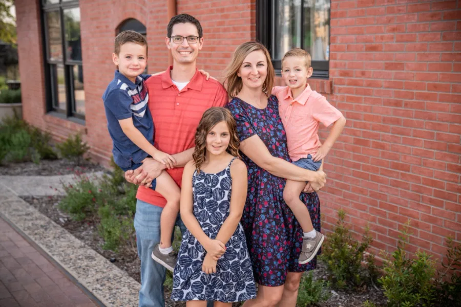 Dr. Talin Pepper smiling with his wife and three children outside their clinic building