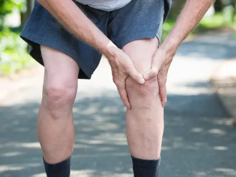 Runner holding his knee in pain, a common sign of an ACL injury