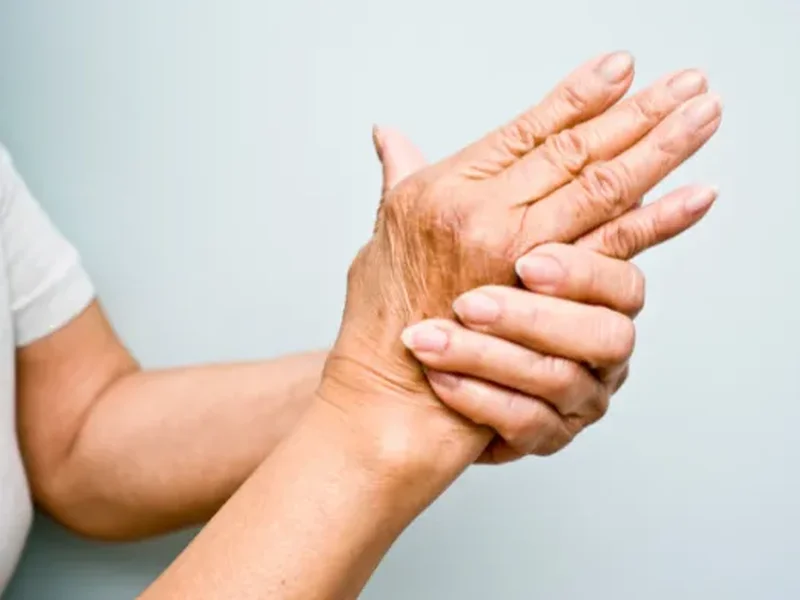 Person holding their hand, showing joint stiffness from arthritis