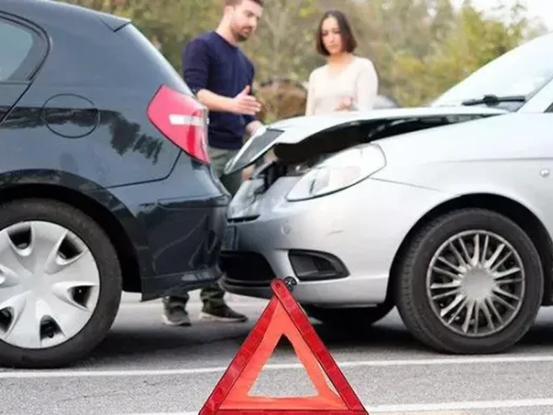 Two cars after a collision, with a road safety triangle in the foreground