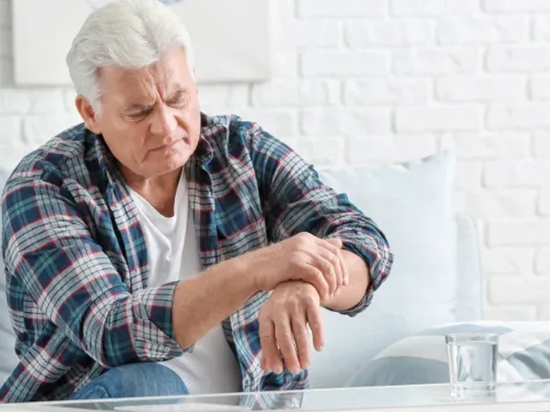 Older man holding his arm, a common sign of Parkinson's tremor