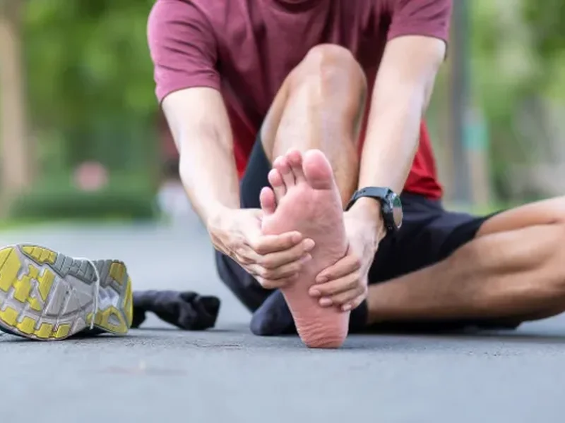 Runner holding his foot in pain, a common sign of plantar fasciitis