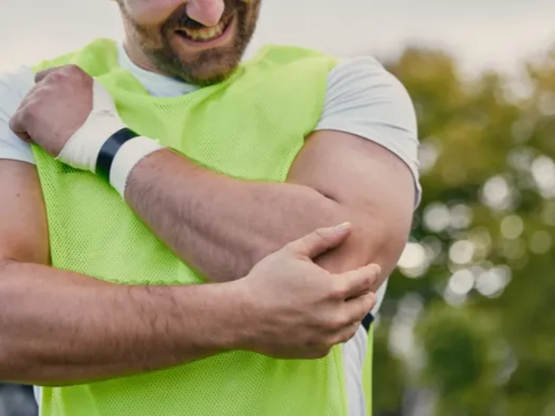 Person holding their elbow in pain, a common sign of tendinitis
