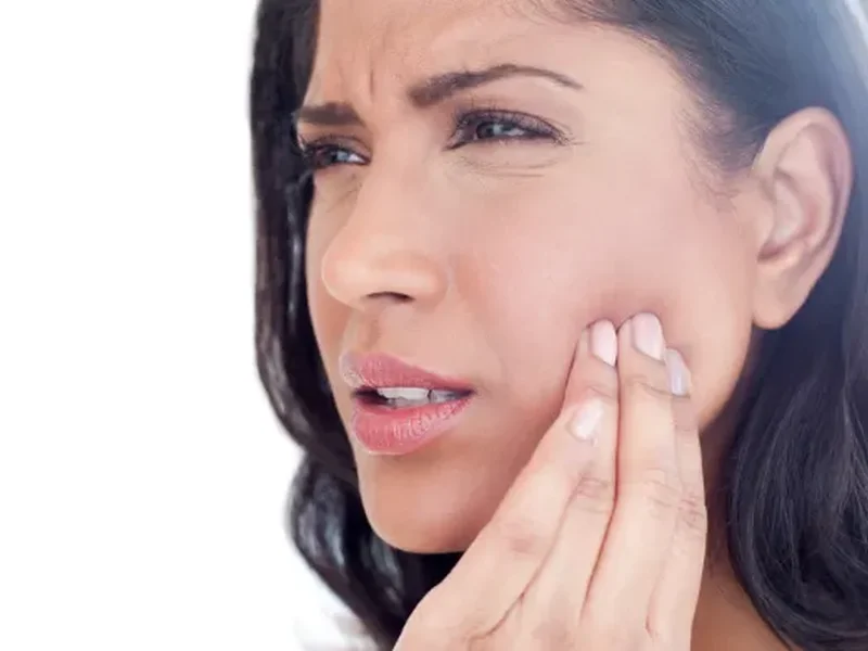 Woman touching her jaw in pain, a common sign of TMJ/TMD