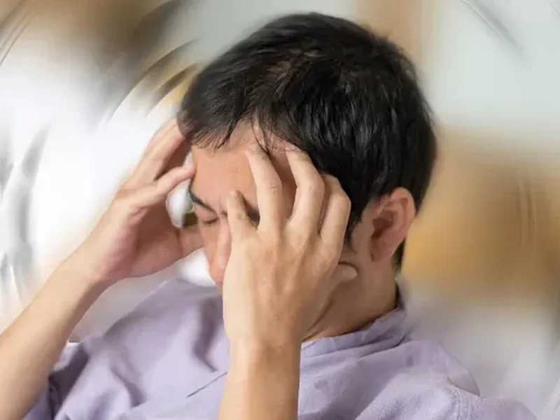 Man holding his head, showing signs of dizziness and vertigo
