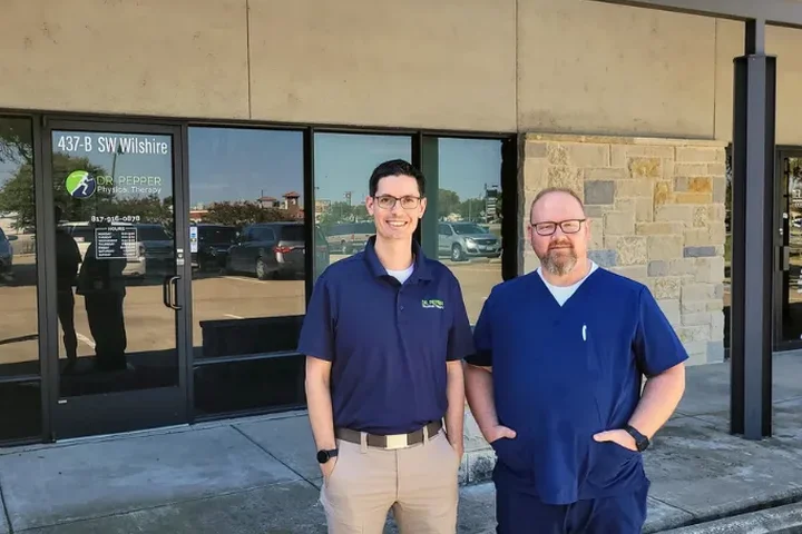 The Dr. Pepper Physical Therapy clinic storefront in Burleson, TX, with two team members outside
